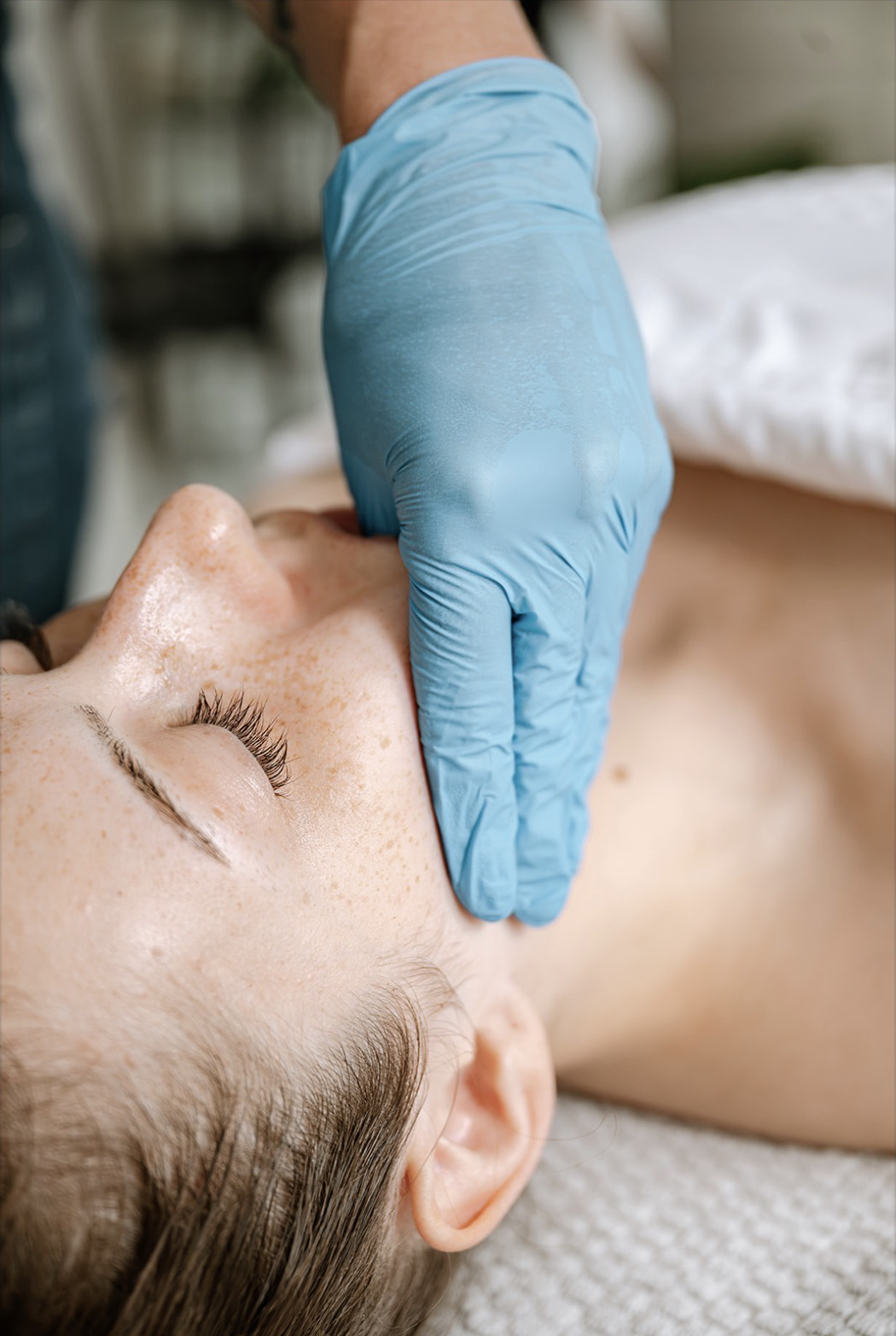 Gloved hands performing intra-oral buccal massage along a client's cheek and jaw